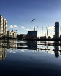 Reflection of buildings in city against clear sky