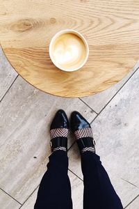 Low section of woman standing with coffee on table