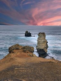 Rock formation on beach against sky during sunset