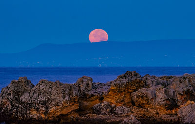 Scenic view of sea and mountain against clear sky