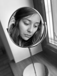 Portrait of a smiling young woman looking through window