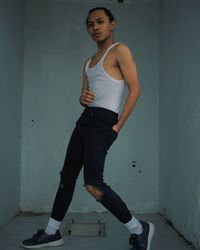 Full length portrait of young man standing against wall