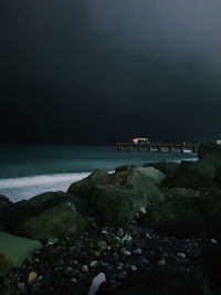 Rocks on beach against sky at night