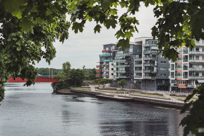 Buildings by river in city against sky