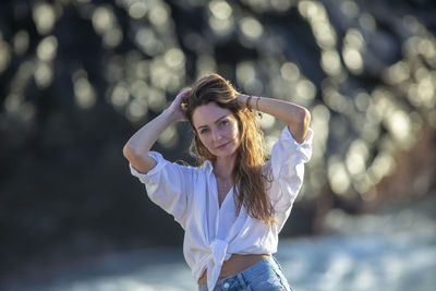 Portrait of young woman looking away while standing outdoors