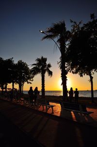 Silhouette people at beach against sky during sunset