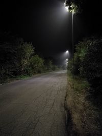 Road amidst trees against sky at night