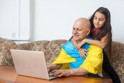 Girl embracing grandfather at home