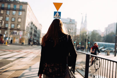 Rear view of woman standing on railing in city