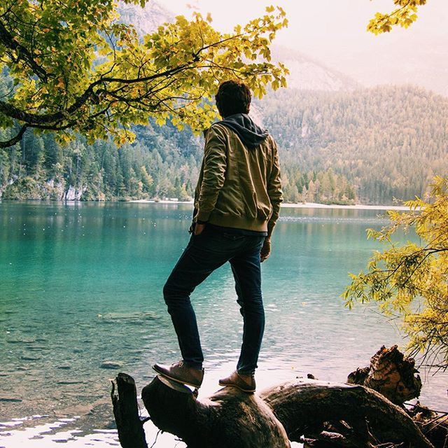 water, tree, full length, rear view, lifestyles, leisure activity, lake, standing, tranquility, tranquil scene, casual clothing, beauty in nature, nature, scenics, three quarter length, sky, sitting, river