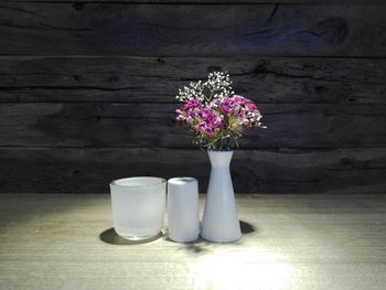 Close-up of flower vase on table against wall