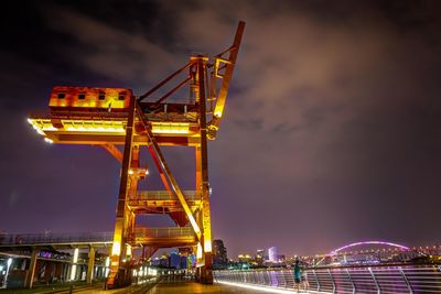 Low angle view of illuminated crane against sky at night