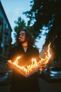 Young man standing against illuminated fire