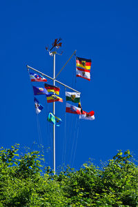 Low angle view of various colorful flags against clear blue sky