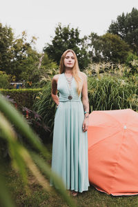 Portrait of young woman while standing against plants