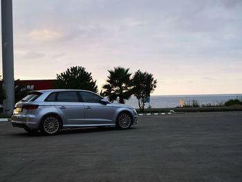 Car parked by road against sky in city