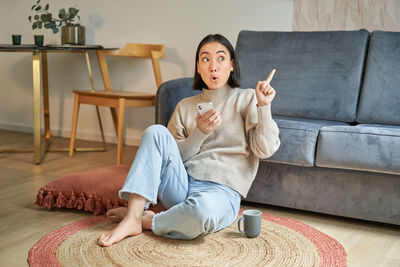 Portrait of young woman sitting on sofa at home