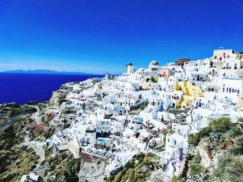 High angle view of townscape by sea against blue sky