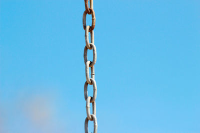 Low angle view of chain against blue sky