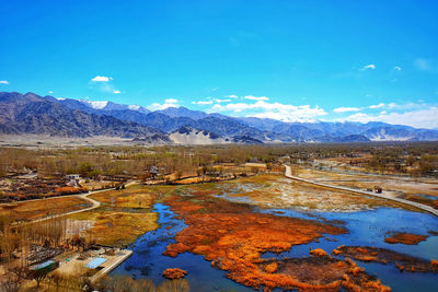 Scenic view of lake and mountains against blue sky