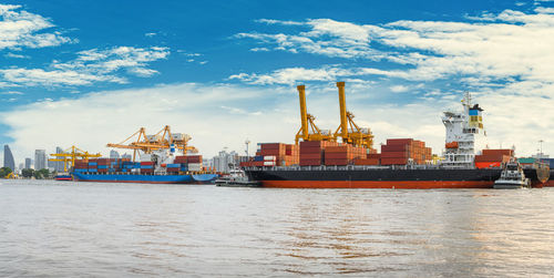 International container cargo ship with working crane bridge in shipyard background, logistic import