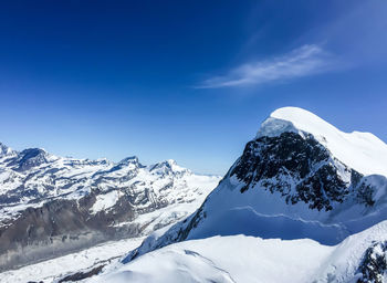 Scenic view of snowcapped mountains against blue sky