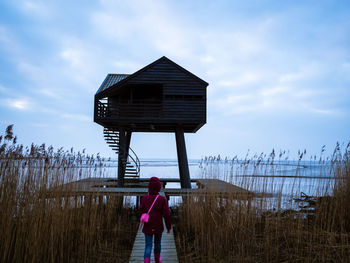 Rear view of woman standing on beach against sky