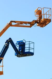 Low angle view of crane against clear blue sky