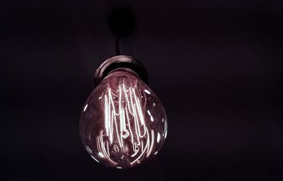 Close-up of illuminated light bulb against black background