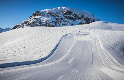 Snow covered mountain and empty ski slope against sky