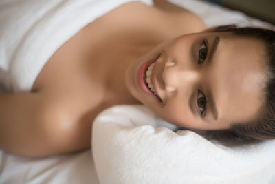 Portrait of smiling young woman lying on massage table in spa