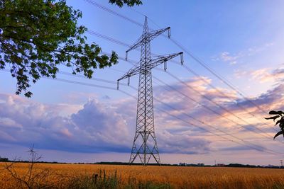 Low angle view of electricity pylon on field against sky