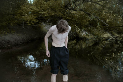 Shirtless man standing in lake