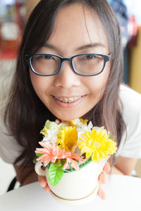 Close-up of smiling young woman holding flowers
