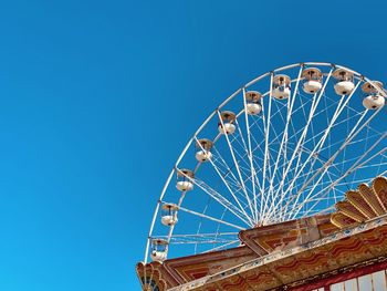 Low angle view of ferris wheel against blue sky