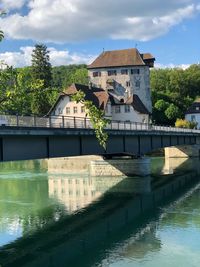 Buildings by river against sky