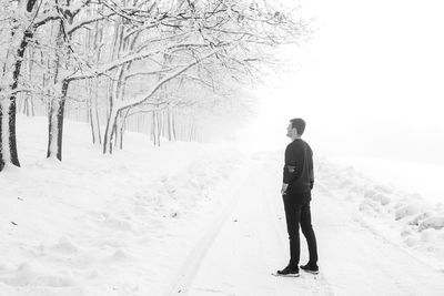 Side view of man standing on snow covered landscape