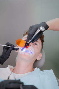 The dentist illuminates the patient's teeth with an ultraviolet lamp to fix the braces.