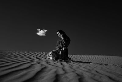 Side view of woman standing at shore against sky