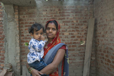 Portrait of mother and daughter against wall