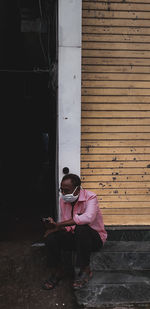 Full length of man sitting against building