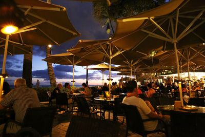 Chairs and tables at restaurant against sky at night