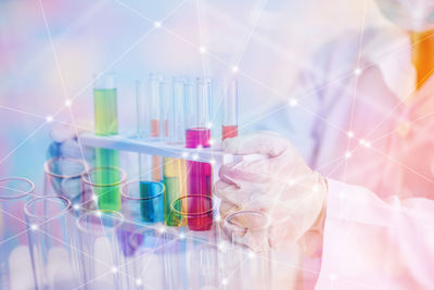 Digital composite image of scientist holding test tubes with colorful liquid