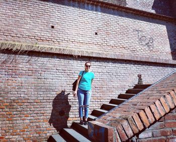Full length portrait of man standing on brick wall