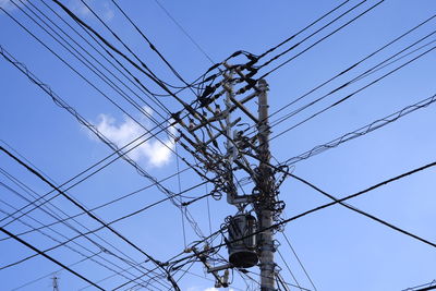 Low angle view of electricity pylon against blue sky