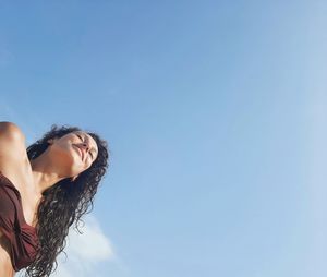 Low angle view of woman against blue sky