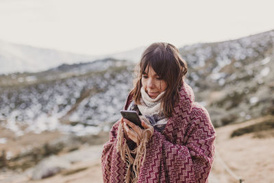 Woman using phone while standing on mountain