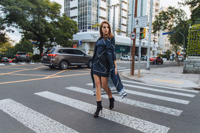 Full length portrait of woman crossing road