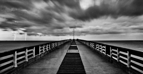 Pier on sea against cloudy sky