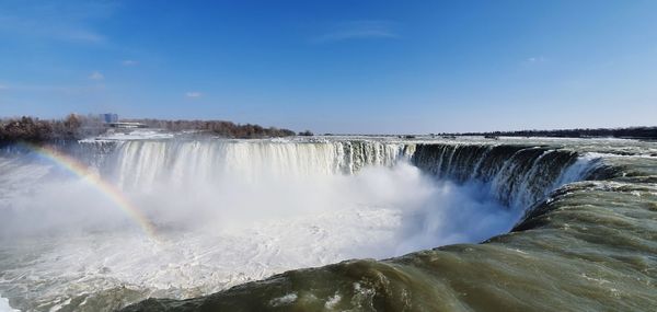 Panoramic view of niagara falls during winter time with a rainbow